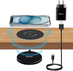 Wireless charging pad, smartphone, power adapter, and cable on a wooden surface.