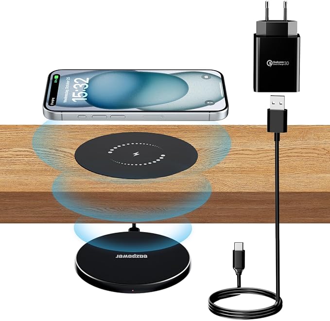 Wireless charging pad, smartphone, power adapter, and cable on a wooden surface.